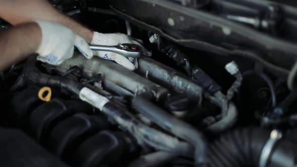 Male Auto Mechanic Changes Spark Plugs in a Car Engine