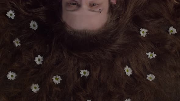 A Man's Reclining Head with Loose Hair and Flowers in It alt