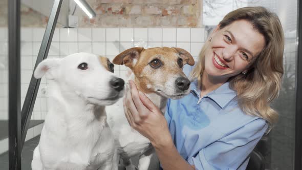 Cheerful Female Vet Smiling to the Camera While Petting Cute Dogs