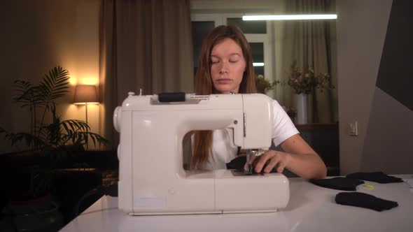  woman Sews a Protective Black Mask on A Sewing Machine