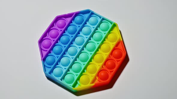 Colorful pop it toy in form of hexagon. View from above on gray background. Rotation. Isolate.