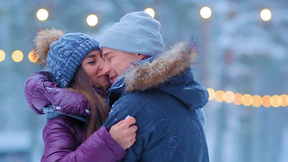 Guy and Girl in Warm Jackets Hug Standing on Skating Rink