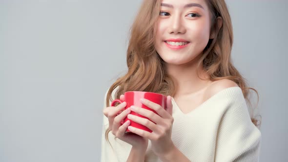 asian female happiness cheerful woman enjoy hot tea or coffee dinkg in red mug studio lifestyle shot alt