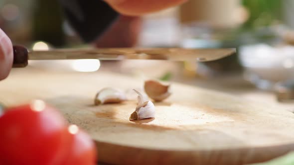 Hands of Male Chef Peeling and Crushing Garlic Clove alt