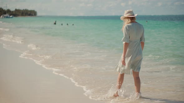 Young Woman Tourist Stands On Shore Enjoying Marine Views. Rocky Seacoast Beach. Tourist Walking. alt