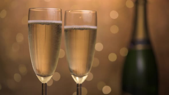 Champagne glasses over holiday bokeh blinking background