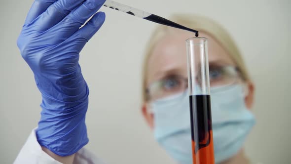 Female Laboratory Scientist Conducts Experiment in Science Lab Looking at Blood Sample with