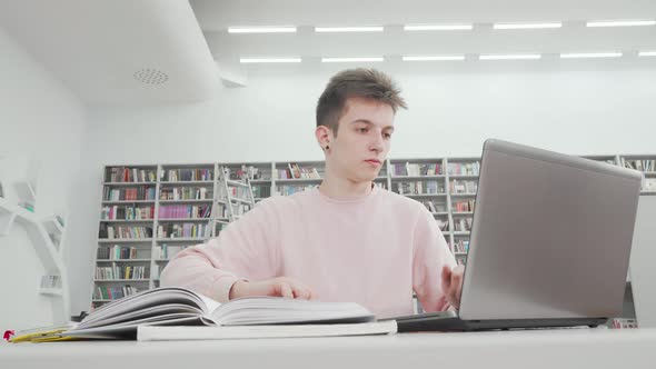 Low Angle Shot of a Male Student Using Laptop at the Library alt