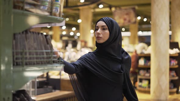 Woman in Hijab Takes Pile of Products From the Shelf in the Supermarket Slow Motion alt