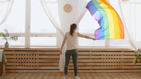 Female Holding LGBT Gay Flag in Hands and Waving on Sunset in Sunny Rays alt