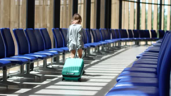 A Child Walks Through the Airport Waiting Room and Carries His Suitcase
