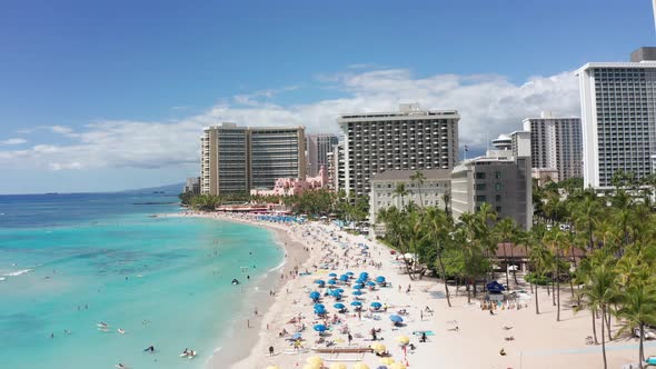 Low aerial shot flying over bustling Waikiki Beach on the island of O'ahu, Hawaii. 4K alt