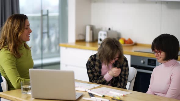Teacher Teaches Young Girls with Down Syndrome Using Laptop Having Fun Together alt