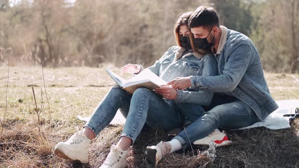 Attractive Young Man Is Hugging His Girlfriend Reading a Book in the Field alt