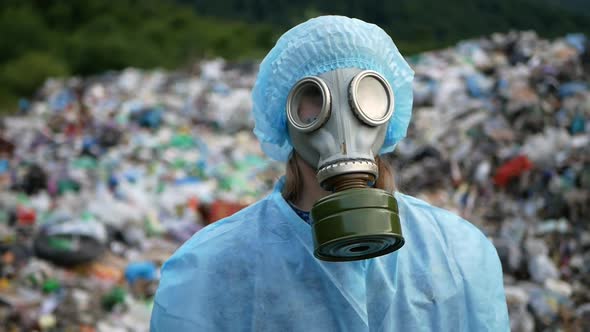 Woman wearing a gas mask on a landfill, a lot of garbage, an ecological ...