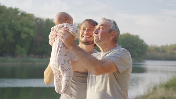 Grand-father Holding Baby Infant in Arms Outside. Grand Parent Bonding with Grand-child. alt