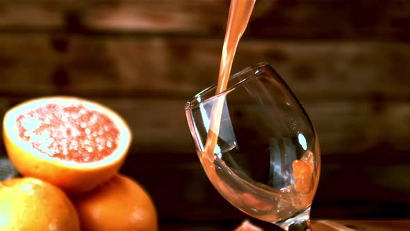 Super Slow Motion a Jet of Grapefruit Juice Pours Into the Glass alt