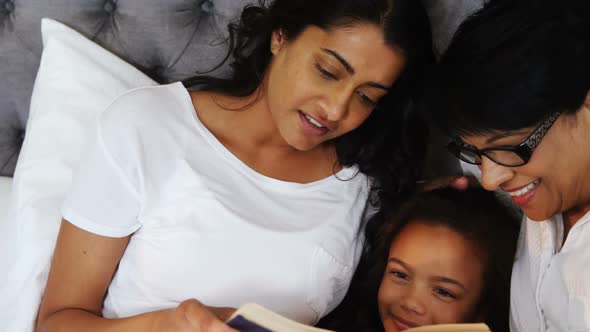 Multi-generation family reading a book in bedroom 4k alt