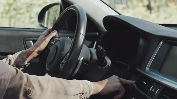 Woman in Hijab Pressing Start Button in Car before Driving alt