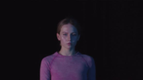 Young Beautiful Woman in Pink Clothes in the Black Studio Looking in the Camera alt