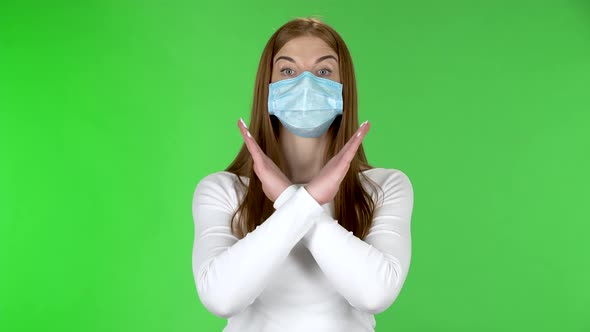 Portrait of Young Girl in Medical Protective Face Mask Looking at Camera and Strictly Gesticulates alt