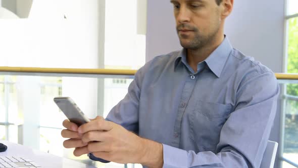 Male executive talking on mobile phone while working at desk 4k alt