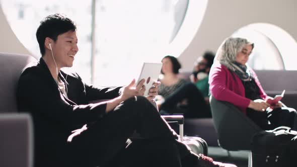 Asian Male watching digital tablet in airport waiting lounge