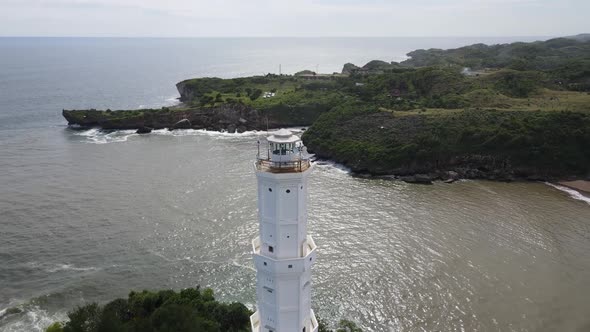 Aerial view of Baron Beach in Gunung Kidul, Indonesia with lighthouse and traditional boat. alt