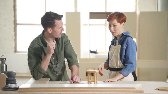 Two Young Carpenters Working As Wood Designers in Small Carpentry Workshop alt