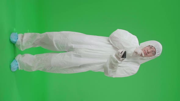 Full Body Of Asian Man Wear Uniform Ppe And Use Mobile Phone Then Thinking In Green Screen Studio alt