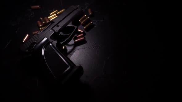 Flashlight Illuminates Pistol and Bullets on Black Concrete Table