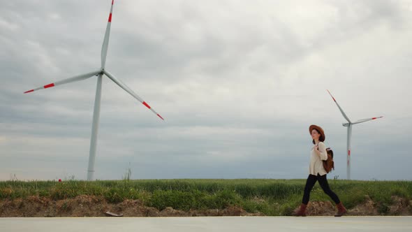 Walking young girl along the road with windmills alt