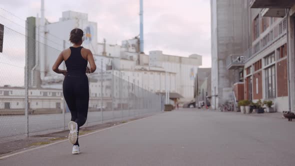 Young Woman In Black Sportswear Jogging Along Harbour alt