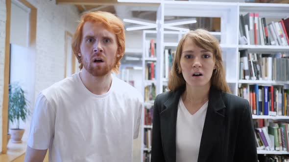 Young Man and Woman Reacting to Loss of Business in Office alt