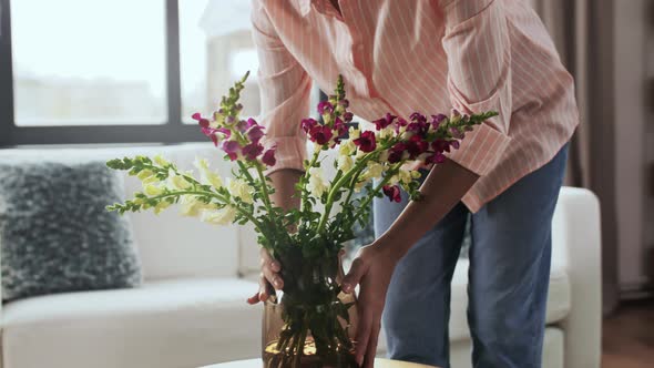 Woman Placing Flowers on Coffee Table at Home