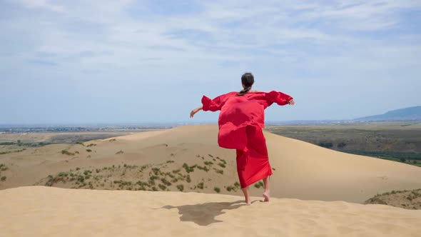 Sexy Brunette Woman in a Red Satin Long Dress Walks on Sand Dunes in the Desert alt