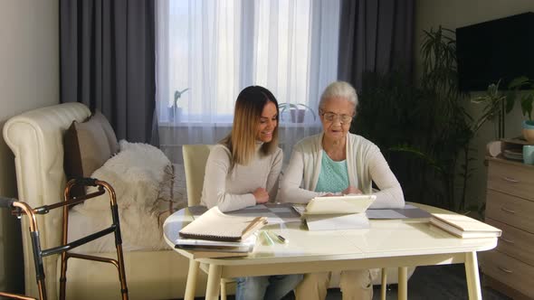 Female Volunteer Teaching Elderly Woman to Use Gadget