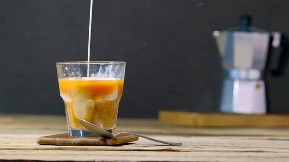 Pouring Cream In A Glass With Iced Coffee