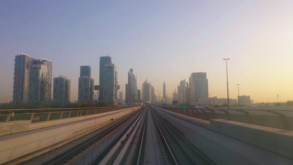 Dubai Futuristic Cityscape Skyline at Sunset, View From Metro Train Front Moving on Railroad alt