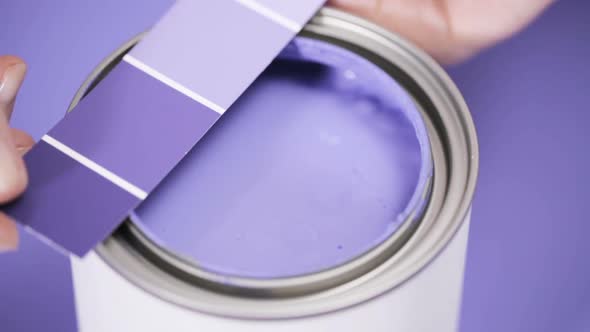 Close up of metal paint can with purple paint and paint swatch. alt