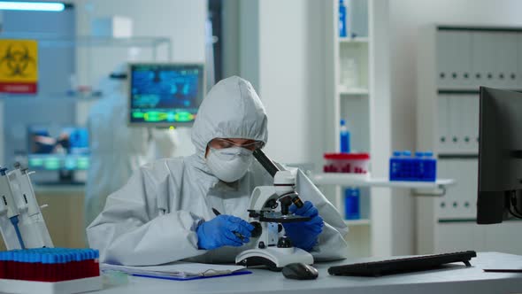 Medical Research Scientist in Ppe Suit Conducting DNA Experiments Under Microscope alt