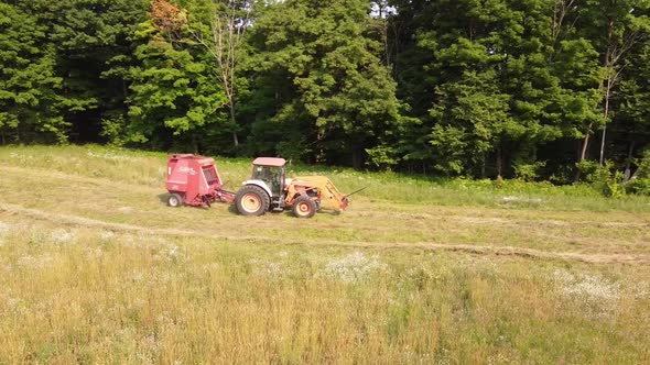 Tractor Pulling A Hay Baler Machine At The Farmland In Rural County Of Leelanau, Michigan. aerial alt