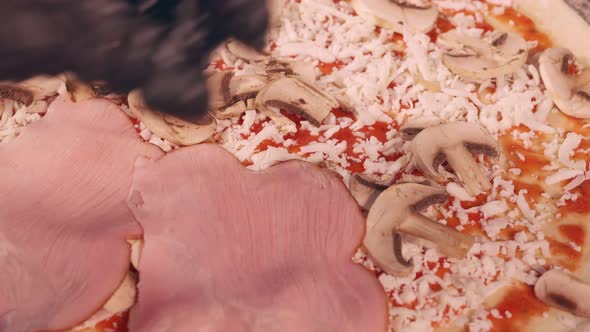 Pizza maker adds sliced bacon to pizza alt