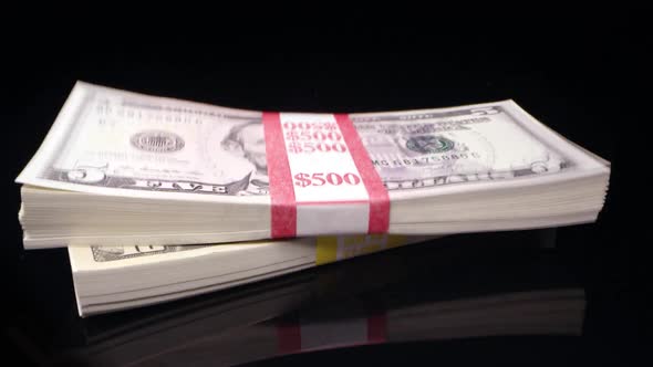 Stacks of Money Dropping onto Black Surface