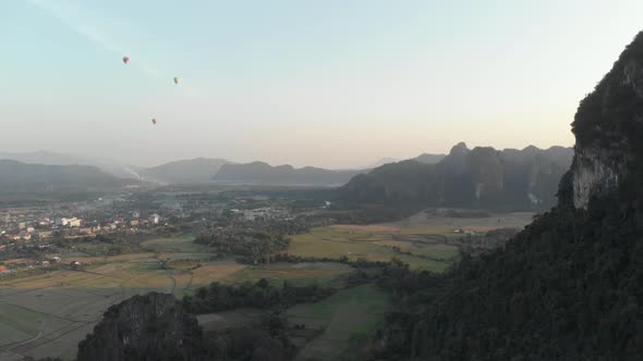 Aerial: Vang Vieng backpacker travel destination in Laos, Asia. Hot air balloons alt