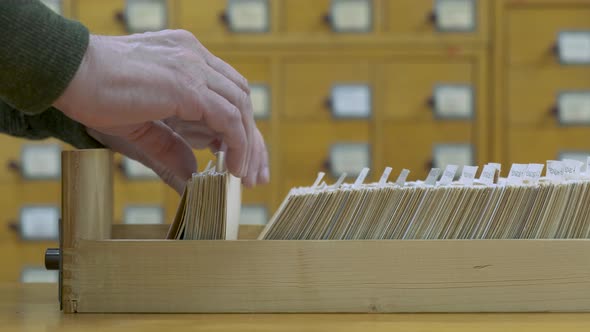 A Male Hand Searching Cards in Old Wooden Card Catalogue alt