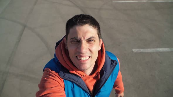 A young Beautiful man in a good mood takes a selfie as he rides on the rollers. Happy boy laughing alt