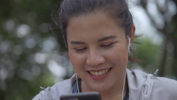 Smile portrait beautiful young Asian woman fitness runner using mobile phone.