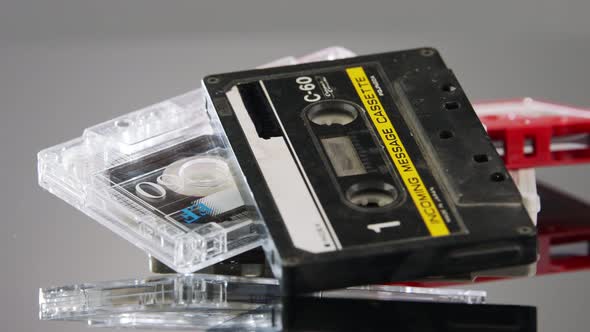 Audio cassettes rotating on a reflective surface in a studio shot. Close up