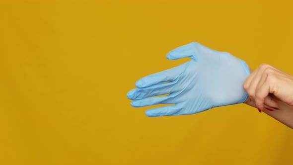 Woman doctor putting on sterile gloves on her hands before surgery close-up. alt